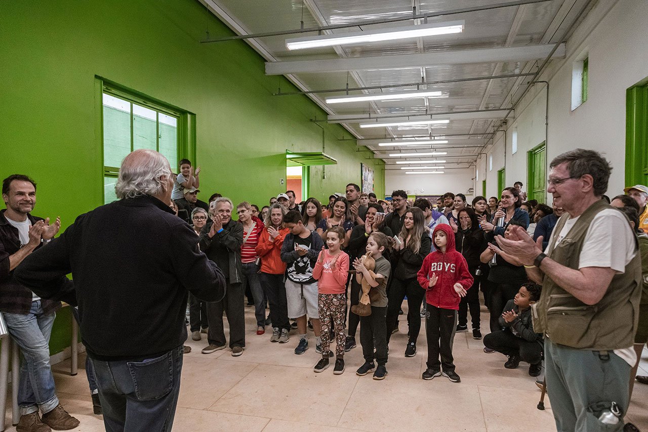 Conjunto de fotos mostra diferentes cenas da ação voluntária Viagem Fantástica: crianças, vestidas com capa de chuva, plantando mudas de árvores, lideranças falando ao microfone e grupo de pessoas reunidas num corredor.