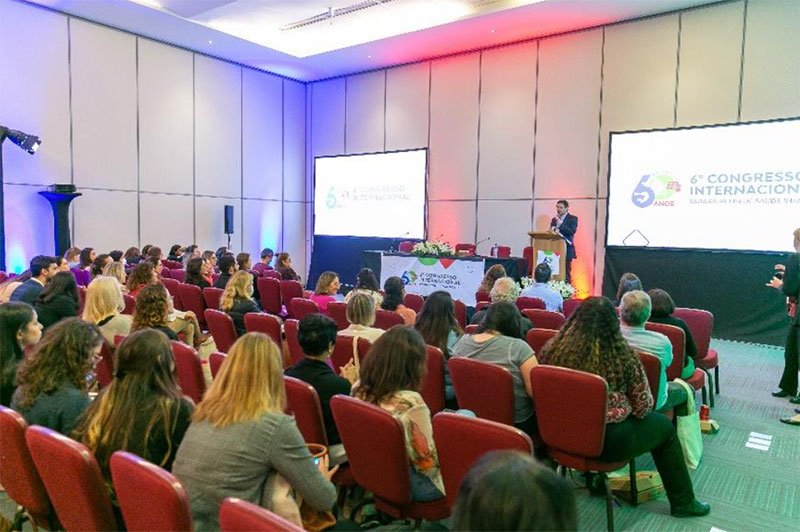 Conjunto de fotos mostra várias cenas do 6º Congresso Internacional Sabará-PENSI de Saúde Infantil: palestrantes sobre o palco, plateia em auditório e dezenas de pessoas em pé, conversando.