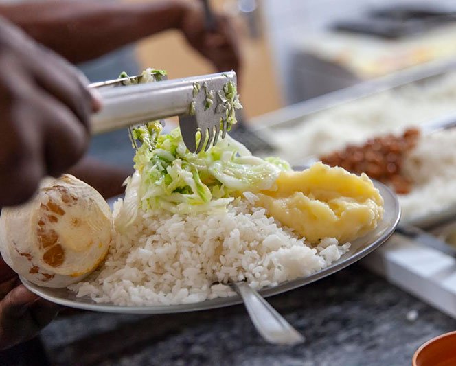 Conjunto de fotos mostra três etapas do projeto: Um triciclo/bicicleta com engradado de comida na bagagem, um homem descendo uma escada com um engradado de bananas nas mãos e uma travessa de comida com arroz, laranja, legumes e purê.