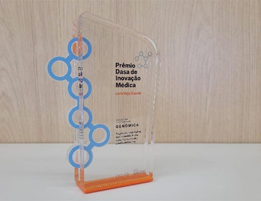 Troféu do Prêmio Dasa de Inovação Médica: ele tem uma base cor de laranja e uma forma vertical, transparente, com círculos da cor azul-claro no lado esquerdo.
